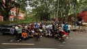 A group of around sixty runners posing together on a tree-lined road beside Cubbon Park after a morning run